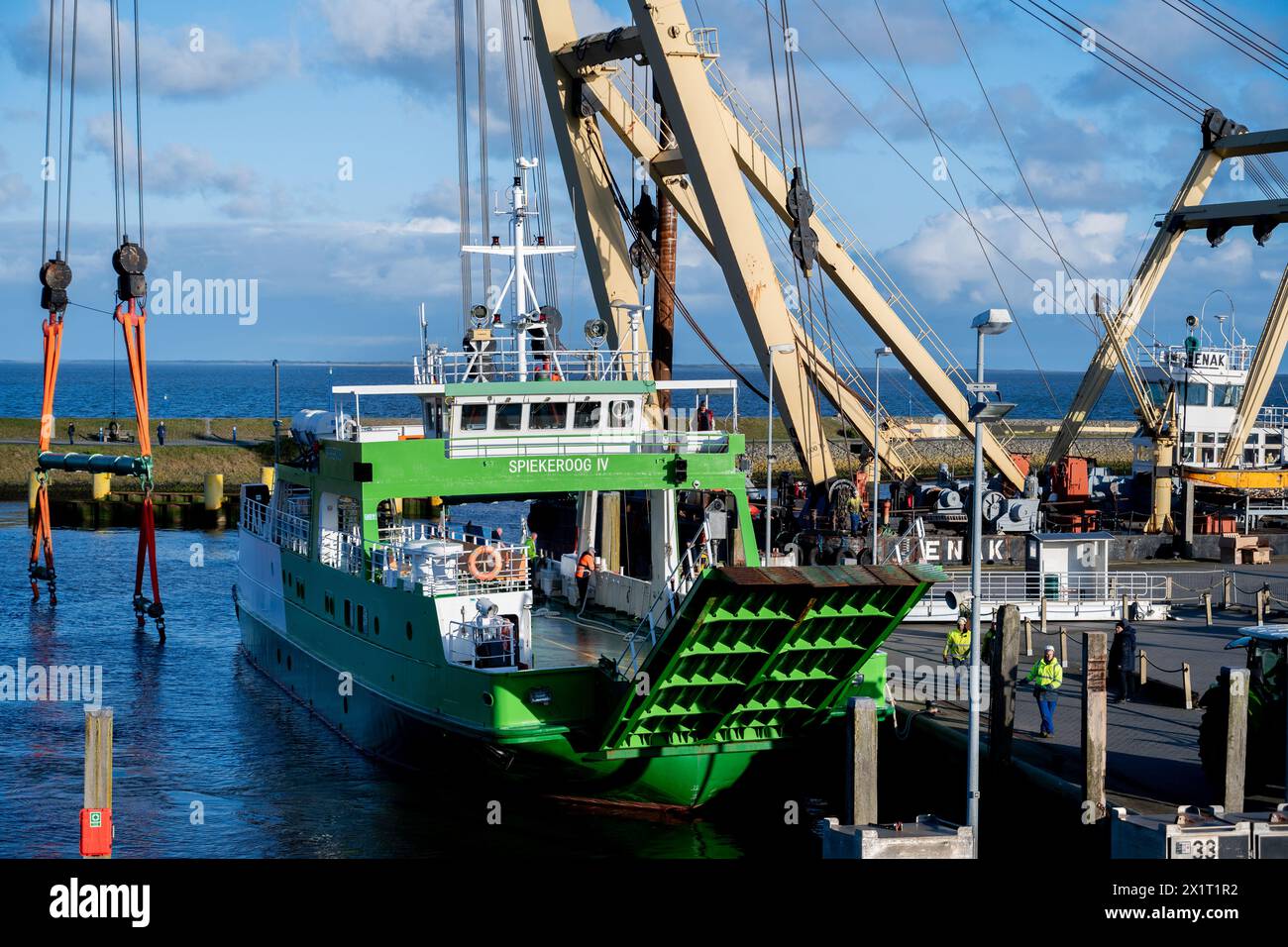 Neuharlingersiel, Germany. 18th Apr, 2024. The ferry 'Spiekeroog IV' lies in the harbor basin after the floating crane 'Enak' lifted the ship from a parking area into the water. The 300-ton ship, which is used for ferry services to the East Frisian island of Spiekeroog, had drifted away from its berth during the storm 'Zoltan' in December 2023 and onto a parking area in the harbour. Credit: Hauke-Christian Dittrich/dpa/Alamy Live News Stock Photo