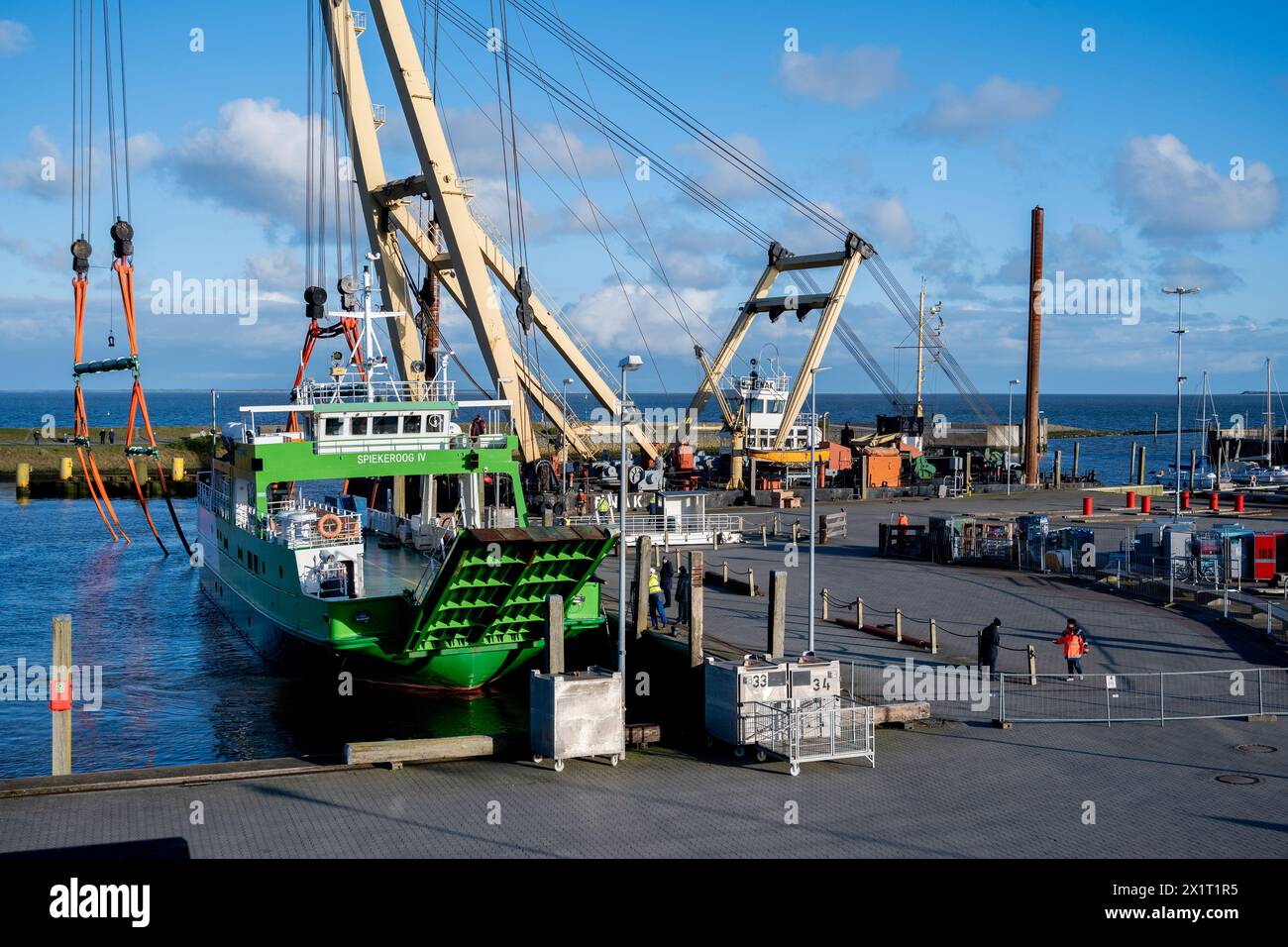 Neuharlingersiel, Germany. 18th Apr, 2024. The ferry 'Spiekeroog IV' lies in the harbor basin after the floating crane 'Enak' lifted the ship from a parking area into the water. The 300-ton ship, which is used for ferry services to the East Frisian island of Spiekeroog, had drifted away from its berth during the storm 'Zoltan' in December 2023 and onto a parking area in the harbour. Credit: Hauke-Christian Dittrich/dpa/Alamy Live News Stock Photo