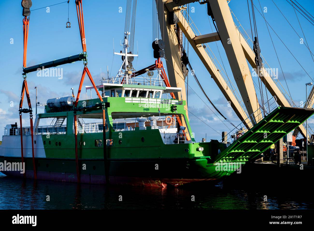 Neuharlingersiel, Germany. 18th Apr, 2024. The floating crane 'Enak' lifts the ferry 'Spiekeroog IV' back into the harbor basin. The 300-ton ship, which is used for ferry services to the East Frisian island of Spiekeroog, had drifted away from its berth during the storm 'Zoltan' in December 2023 and onto a parking area in the harbour. Credit: Hauke-Christian Dittrich/dpa/Alamy Live News Stock Photo