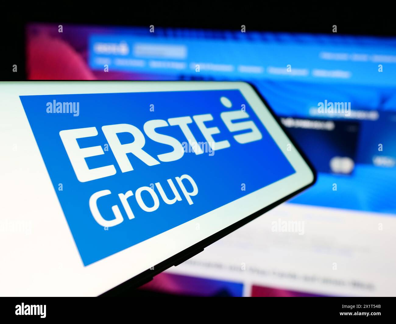 Mobile phone with logo of Austrian financial services company Erste Group Bank AG in front of website. Focus on center-left of phone display. Stock Photo