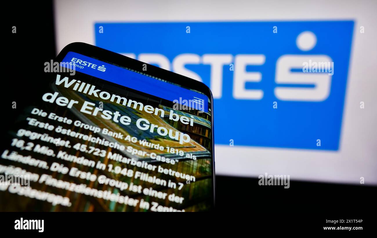 Smartphone with webpage of Austrian financial services company Erste Group Bank AG in front of business logo. Focus on top-left of phone display. Stock Photo