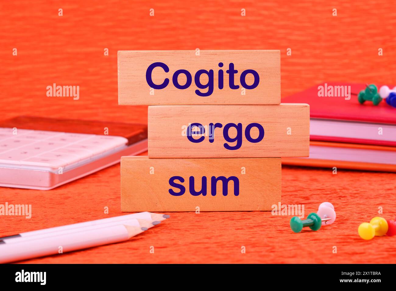 The words Cogito Ergo Sum or I think Therefore I Am on a wooden block next to office supplies Stock Photo