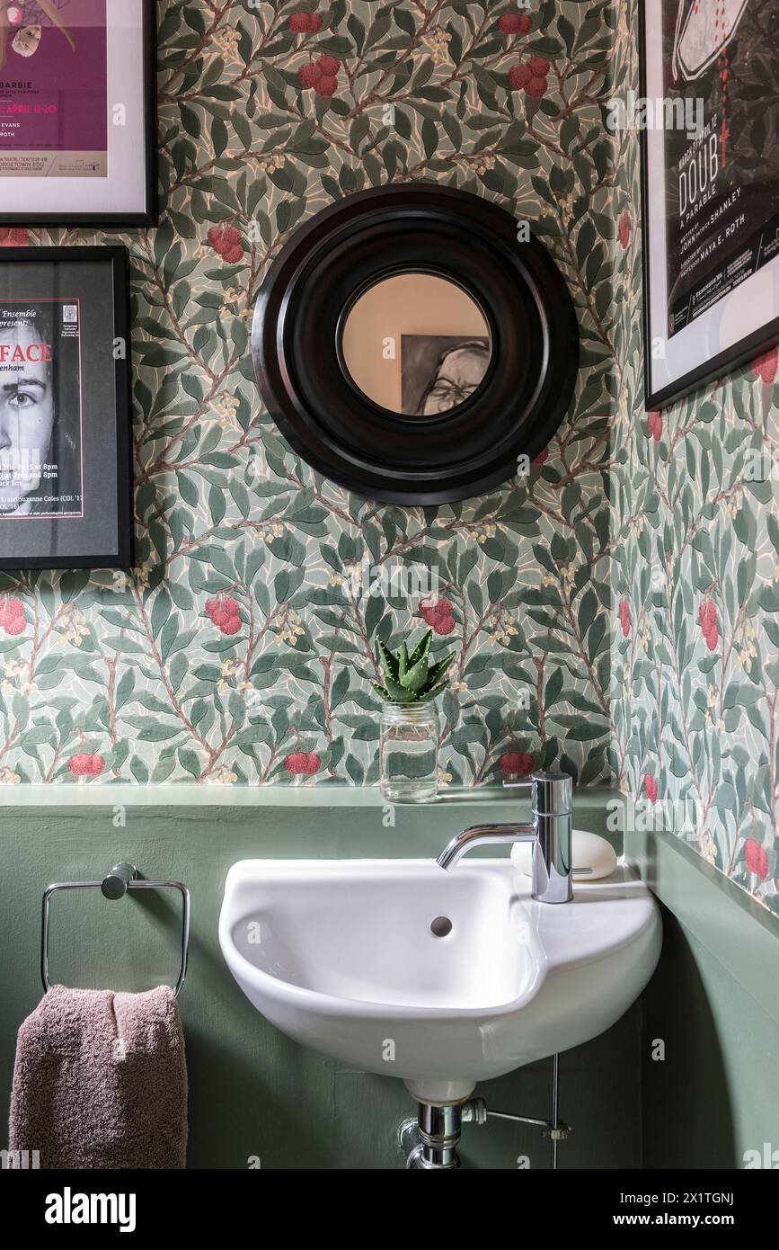 Mirror above basin in floral papered cloakroom of Chelsea  home, London, UK Stock Photo