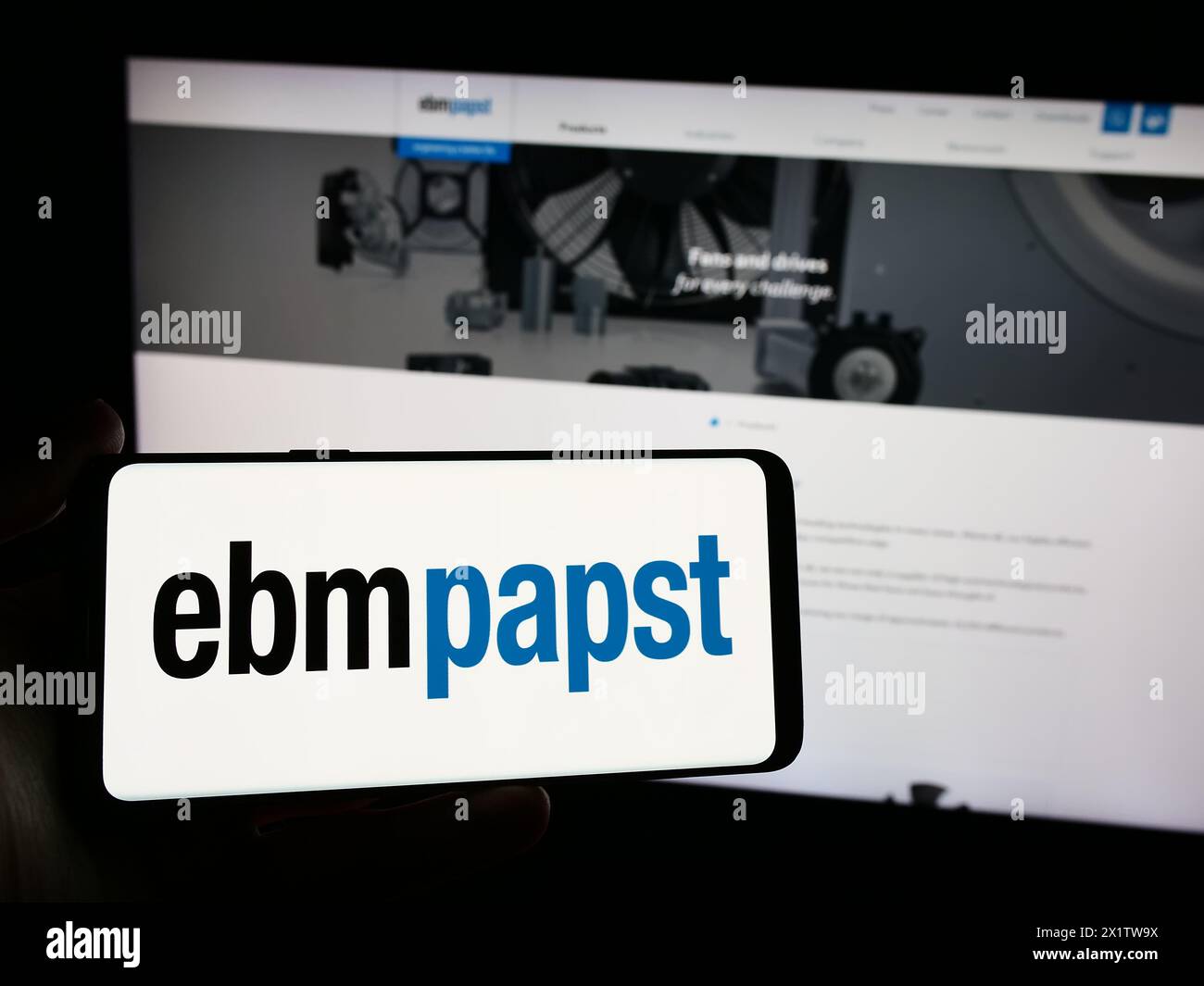 Person holding smartphone with logo of German electric motor company EBM-Papst Gruppe in front of website. Focus on phone display. Stock Photo