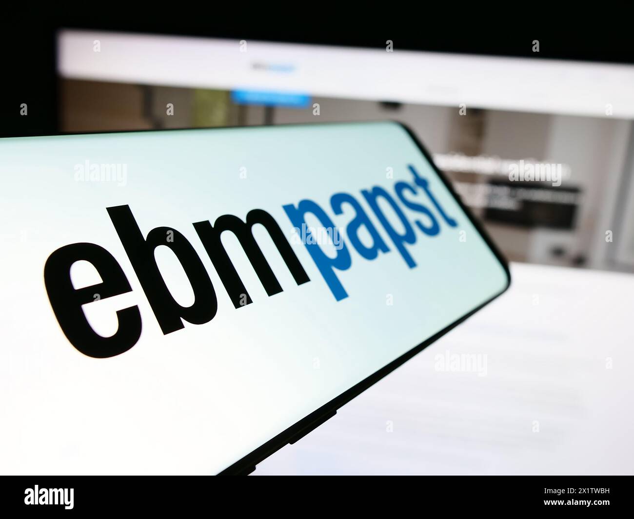 Mobile phone with logo of German electric motor company EBM-Papst Gruppe in front of business website. Focus on left of phone display. Stock Photo