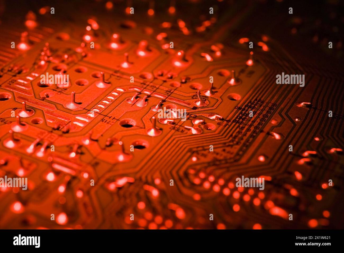 Close-up of red lighted electronic computer circuit board with silver solder points and lines, Studio Composition, Quebec, Canada Stock Photo