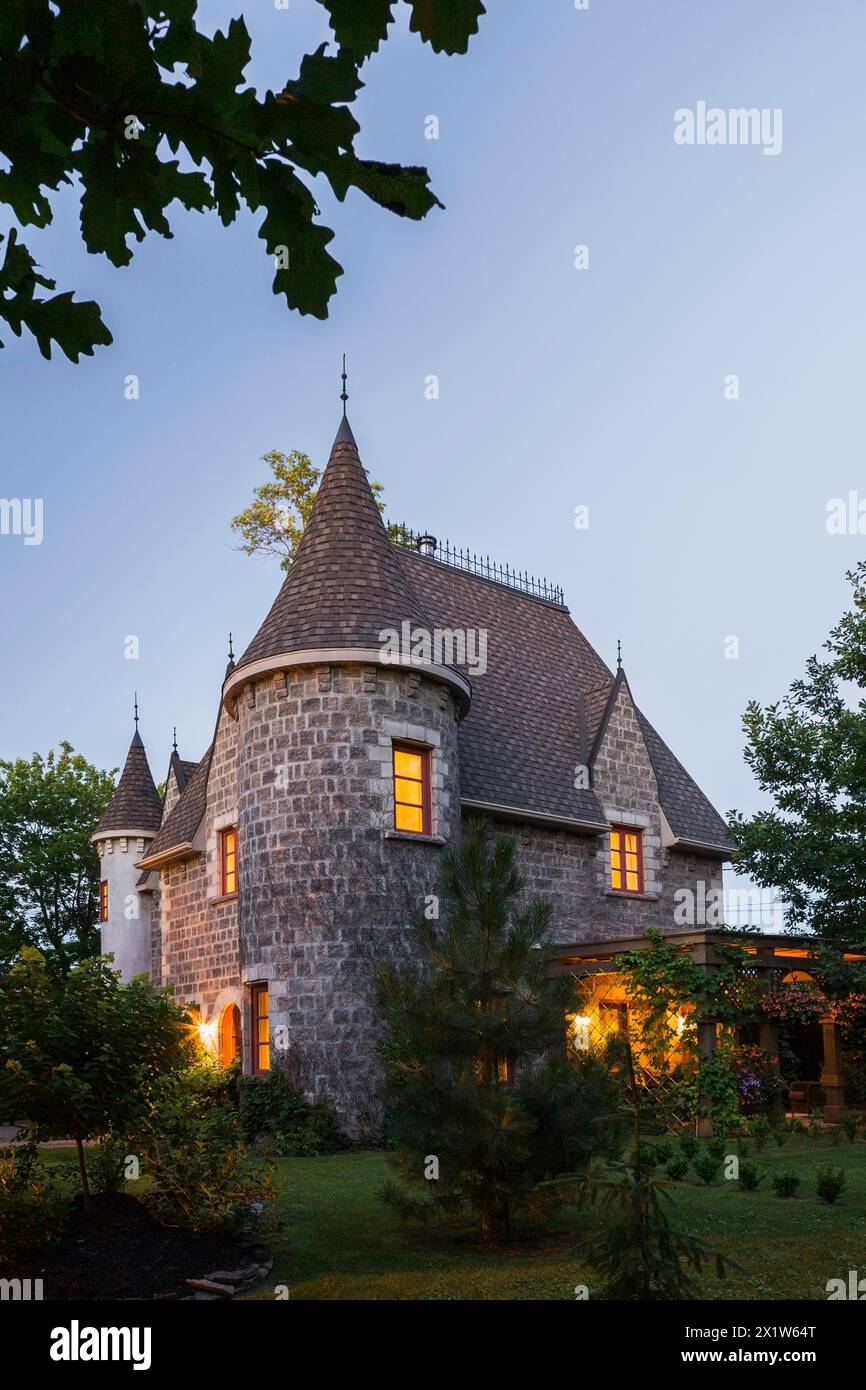 2006 reproduction of a 16th century grey stone and mortar Renaissance castle style residential home facade at dusk in summer, Quebec, Canada Stock Photo
