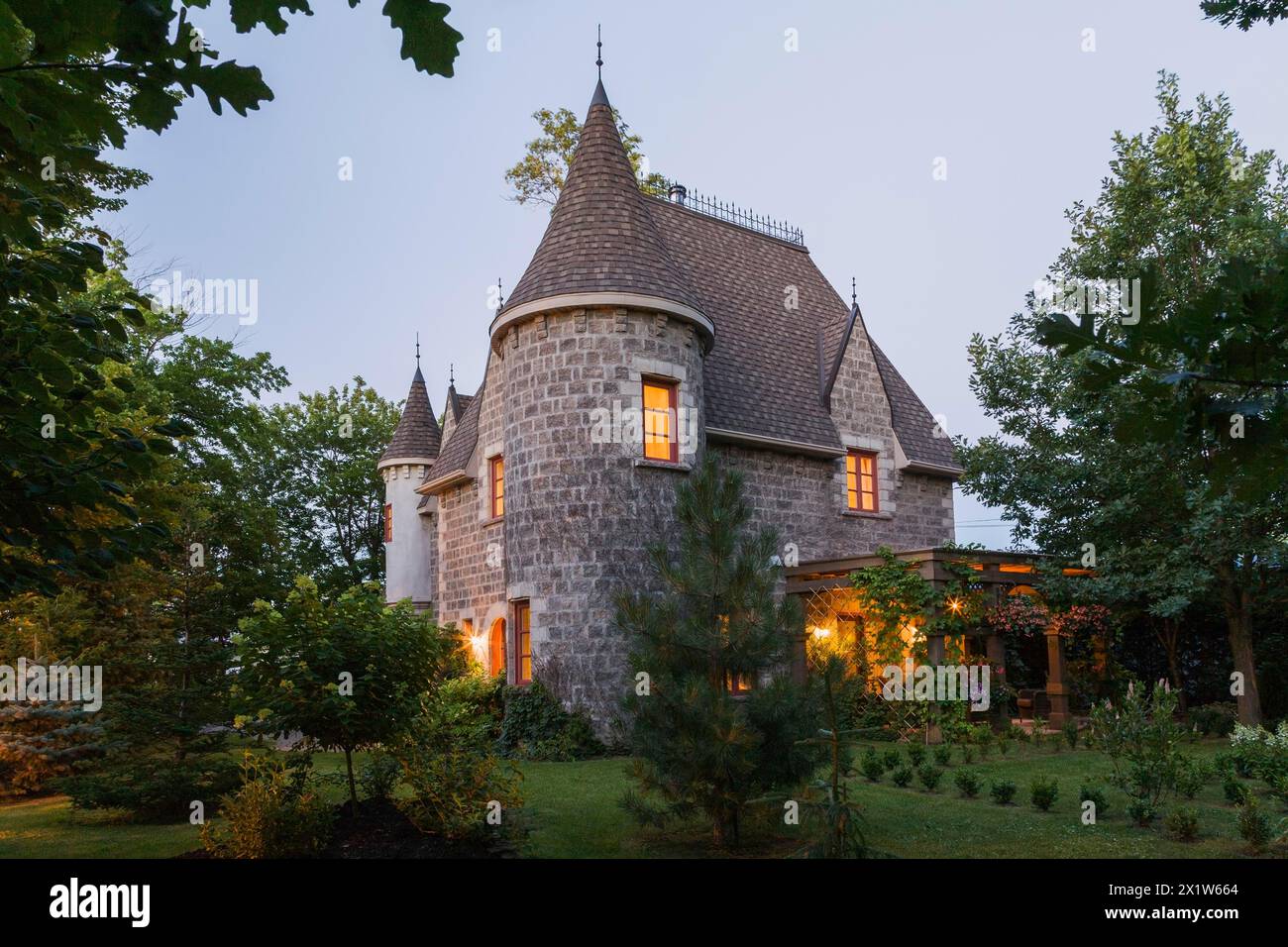 2006 reproduction of a 16th century grey stone and mortar Renaissance castle style residential home facade at dusk in summer, Quebec, Canada Stock Photo