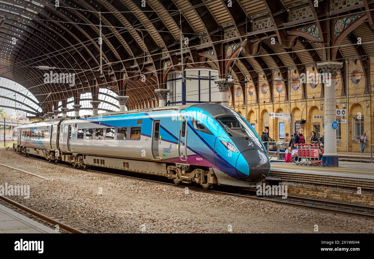 Train Columm A modern train stands at a historic railway station platform under a ...