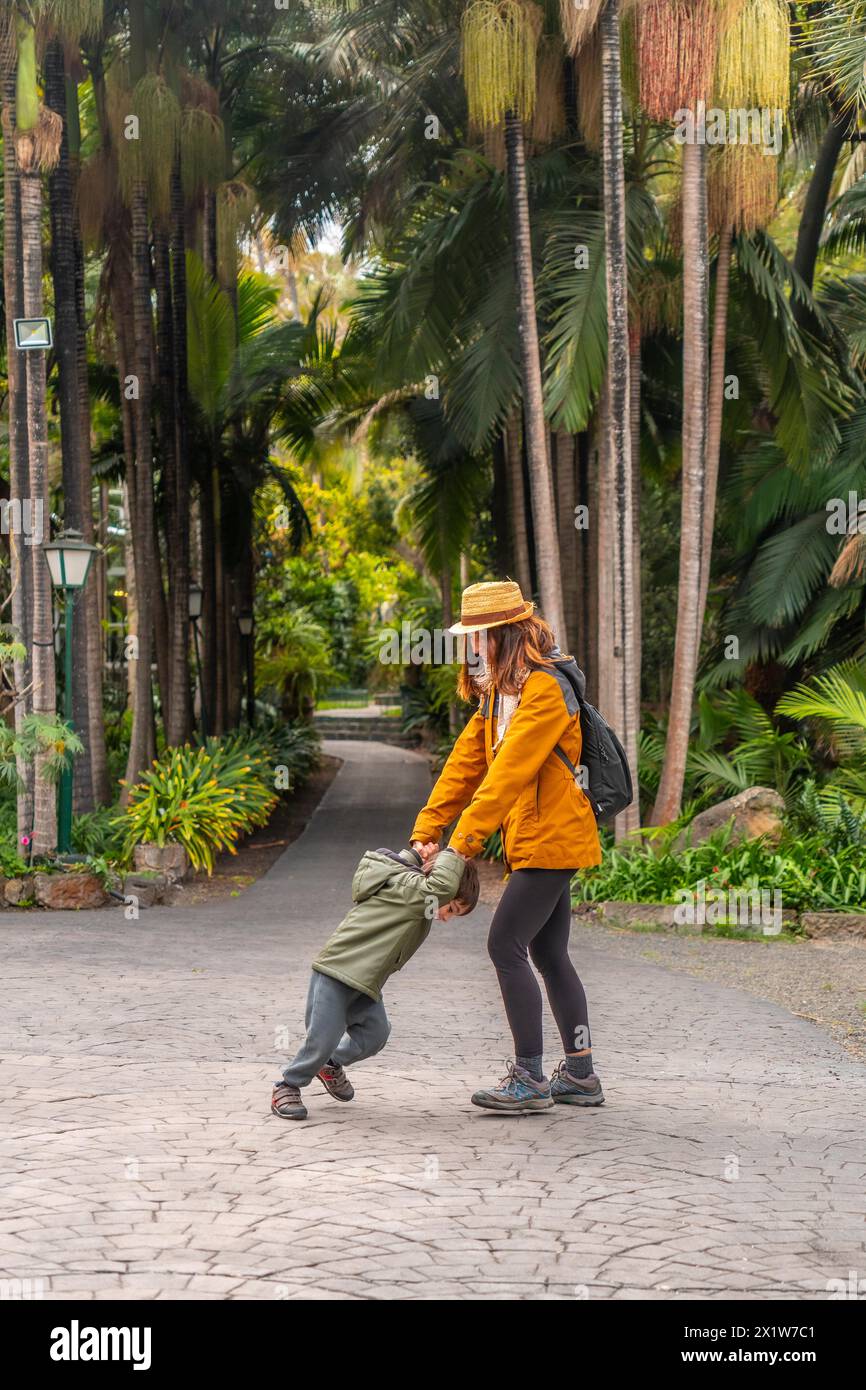 A mother with her son smiling enjoying in a tropical botanical garden with many palm trees Stock Photo