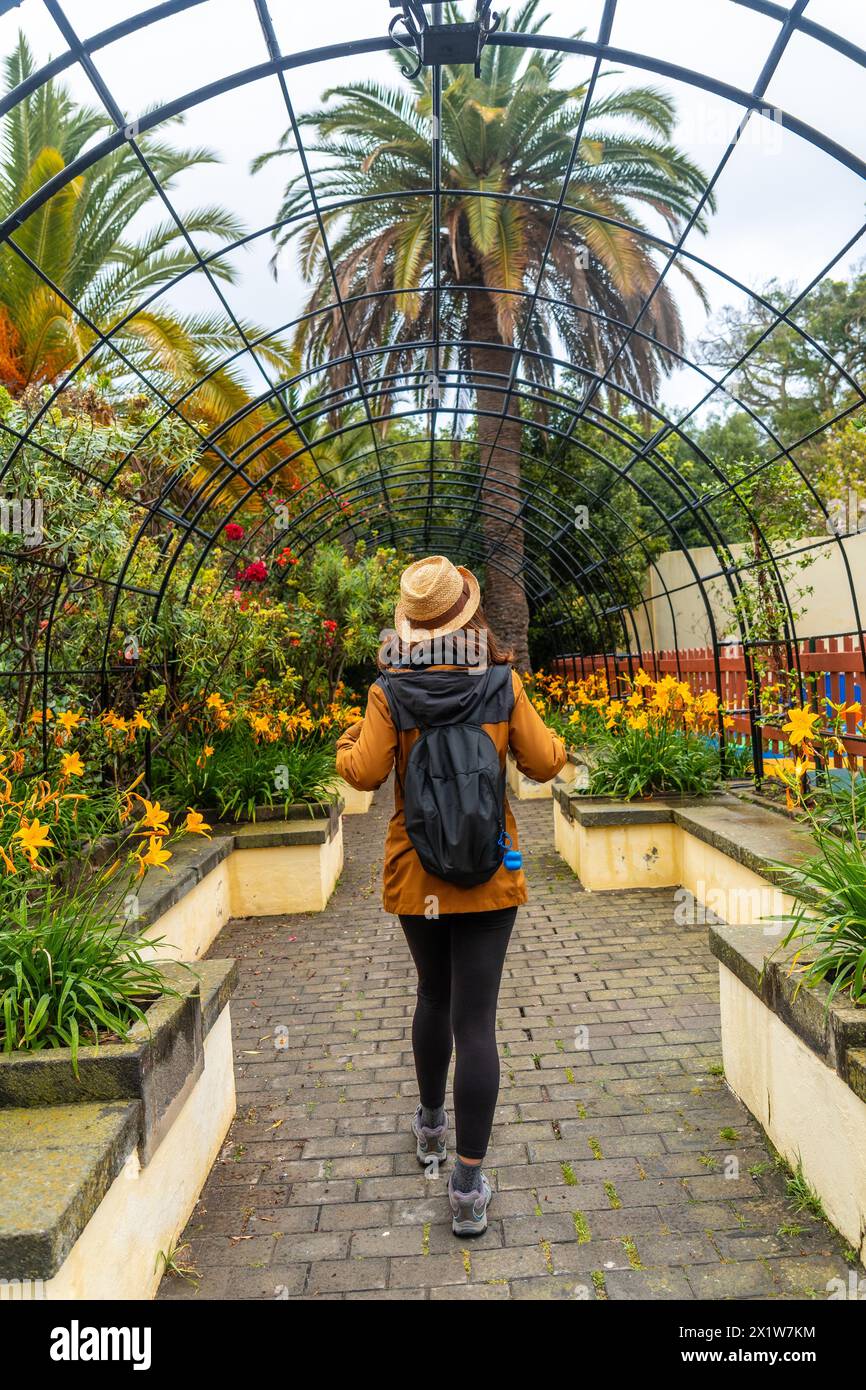 A woman walking through a beautiful botanical garden, a sustainable