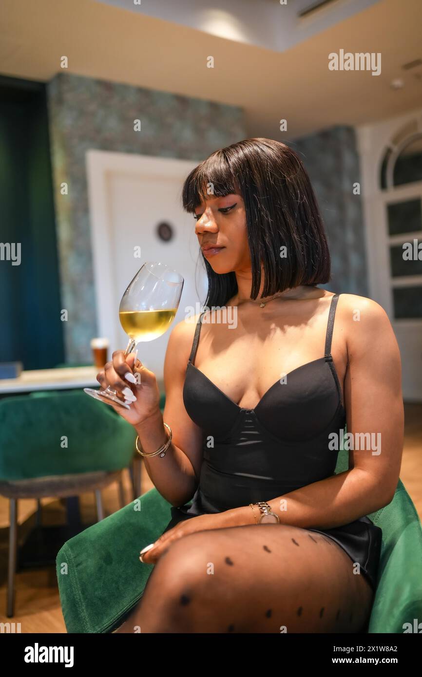 Chic african woman drinking wine in a fine restaurant with comfortable chairs Stock Photo