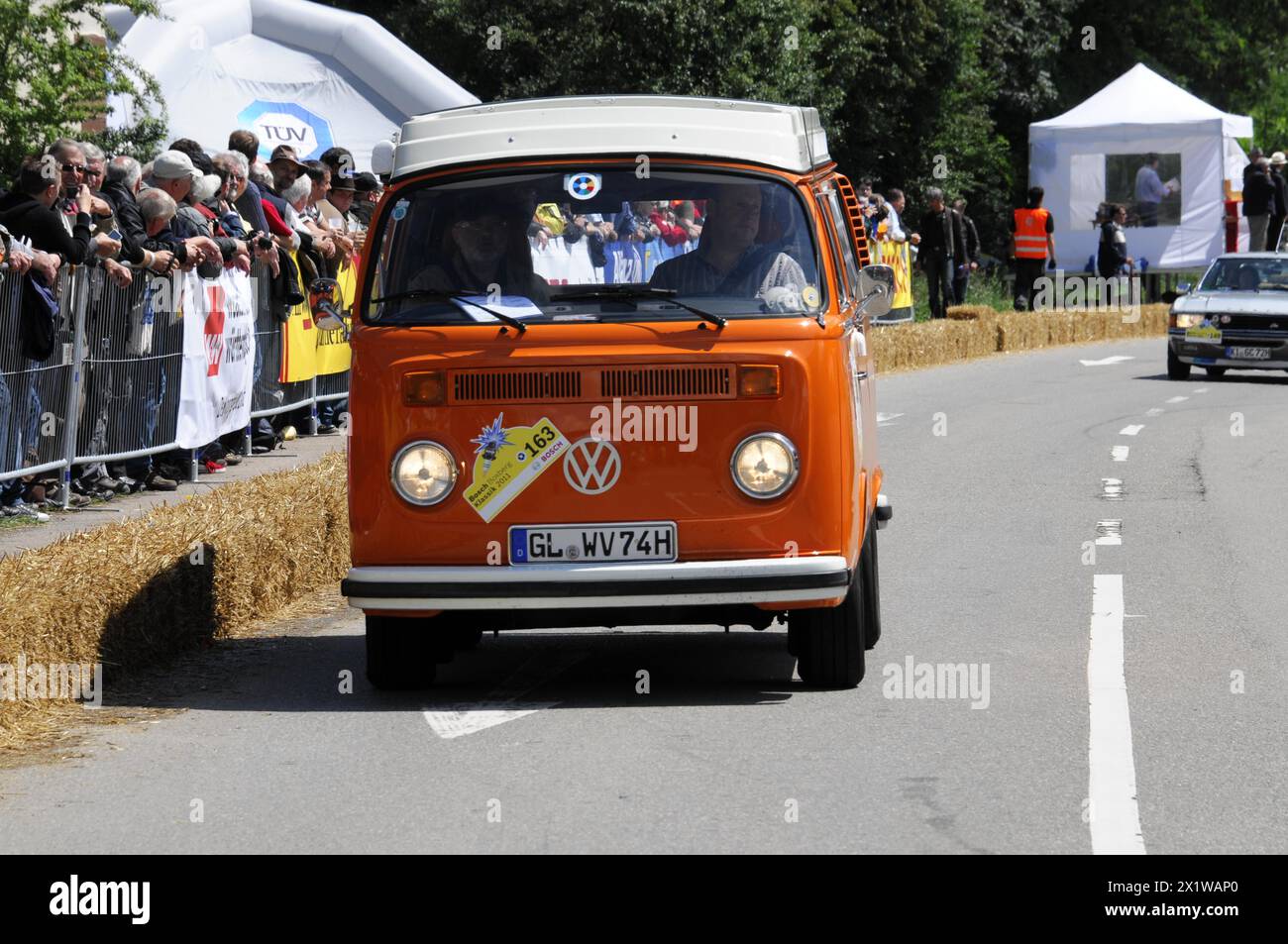 An orange Volkswagen bus drives past a crowd at a race, SOLITUDE REVIVAL 2011, Stuttgart, Baden-Wuerttemberg, Germany Stock Photo