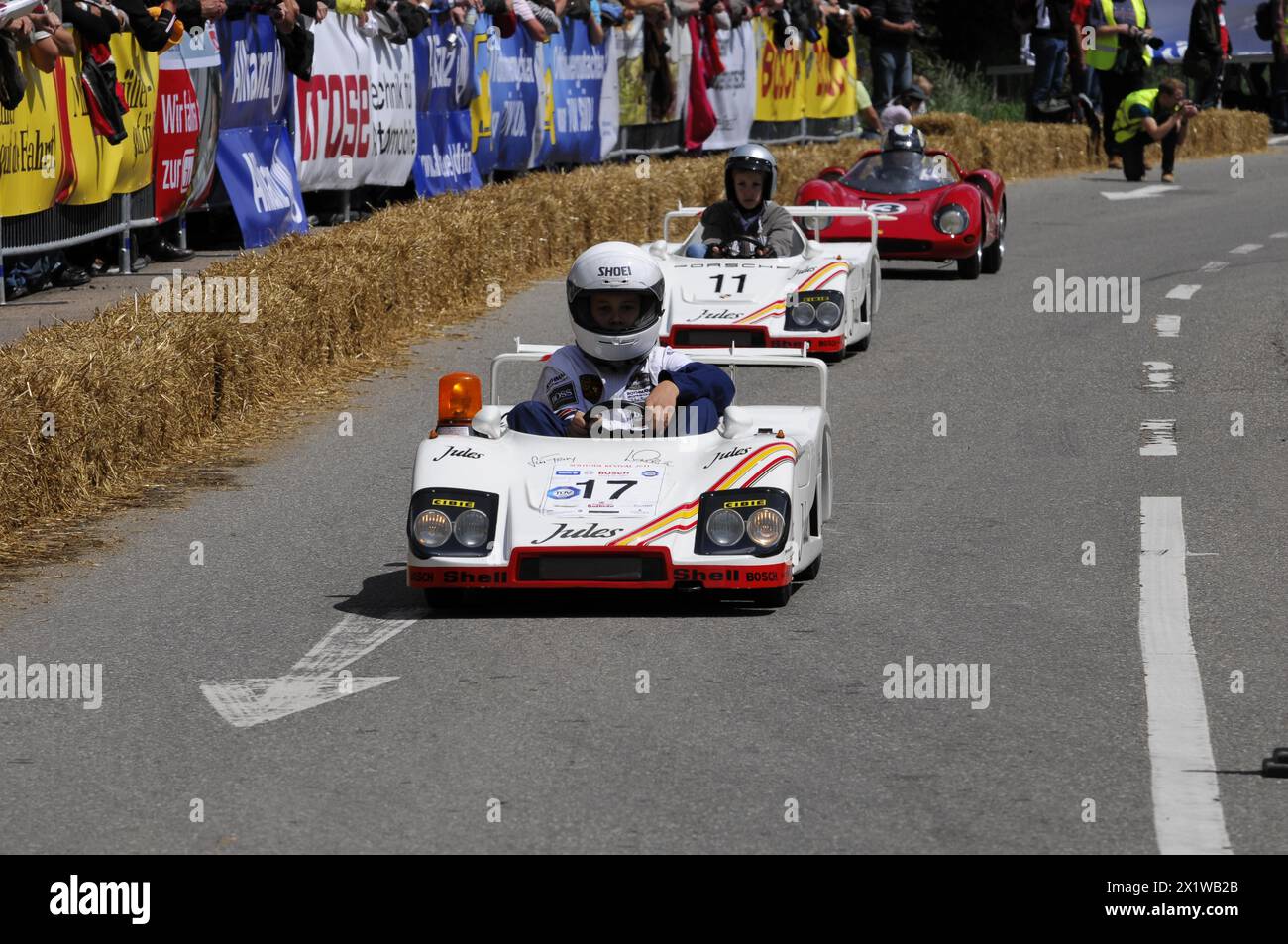 Two people in white racing suits steer their soapboxes during a race