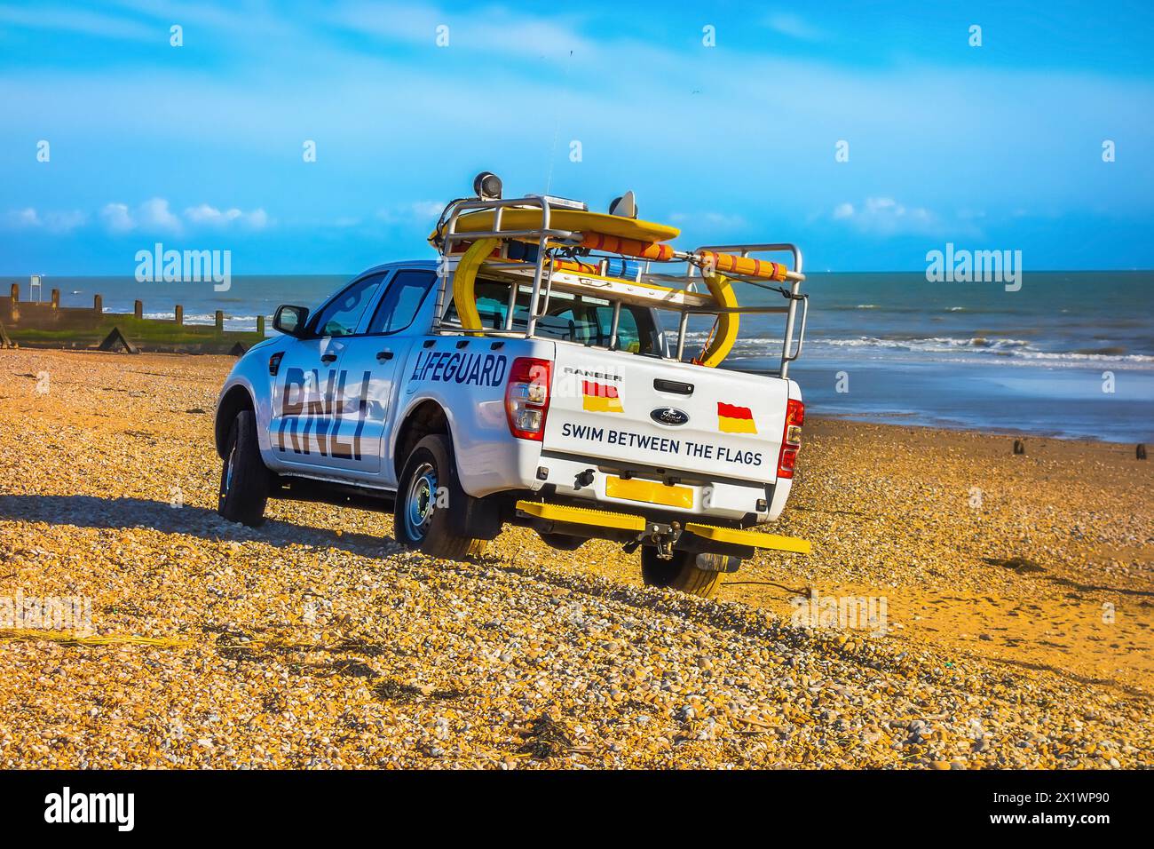 RNLI Lifeguard patrolling the beach in a Ford Ranger pickup truck, Camber Sands East Sussex England Stock Photo