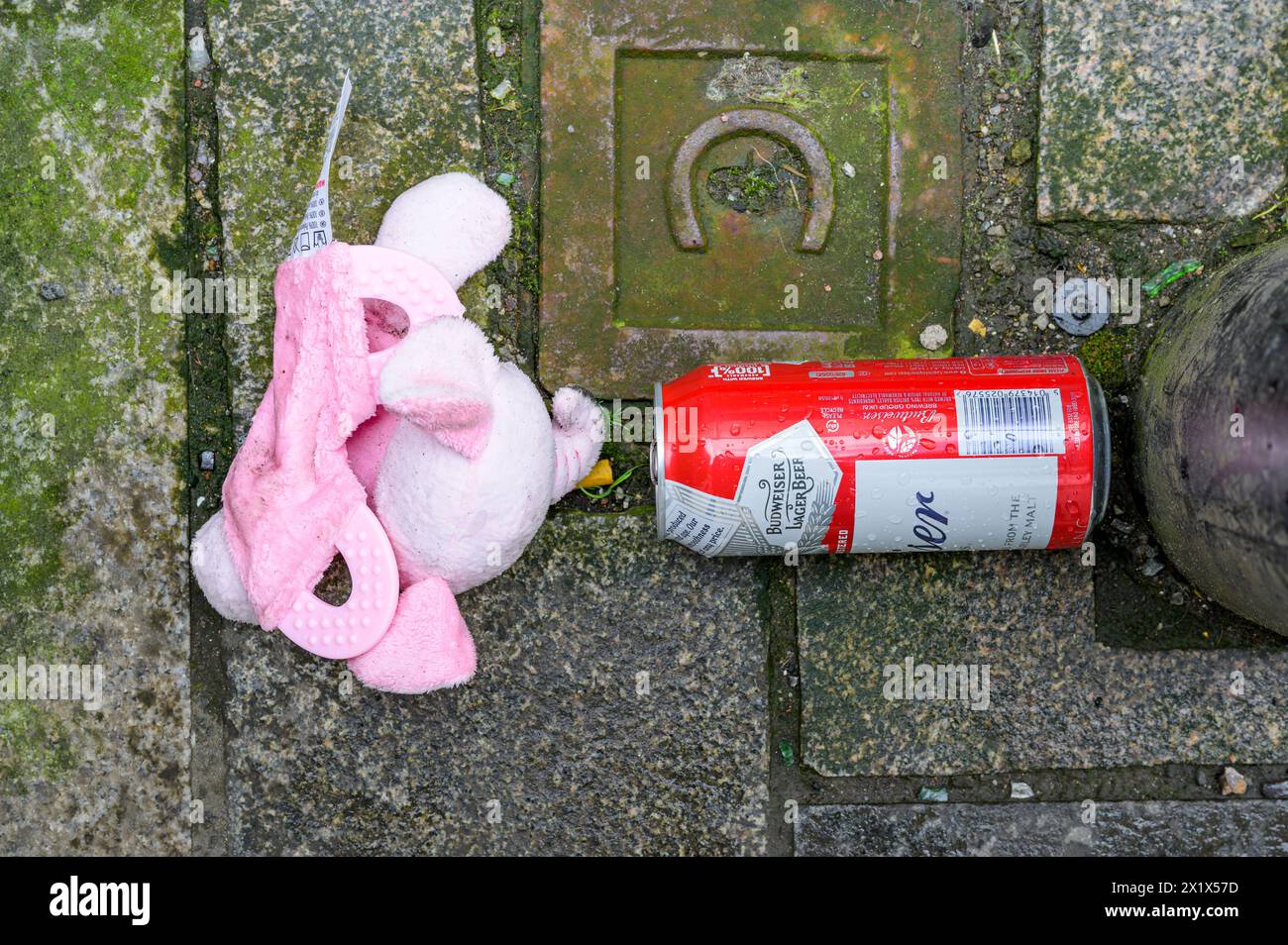 Child's pink toy beside a can of lager on a pavement, UK Stock Photo