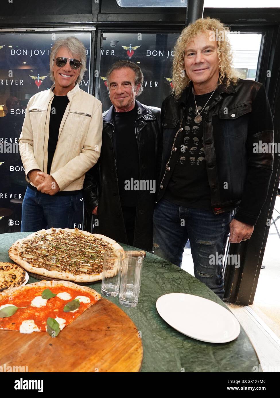 Jon Bon Jovi, Tico Torres, and David Bryan of American rock band Bon Jovi with fans during a pizza party and listening event for their new album 'Forever' in central London. Fans invited to the listening event for the album, which is released on June 7, were surprised when their music idols joined the London gathering. Picture date: Thursday April 18, 2024. Stock Photo