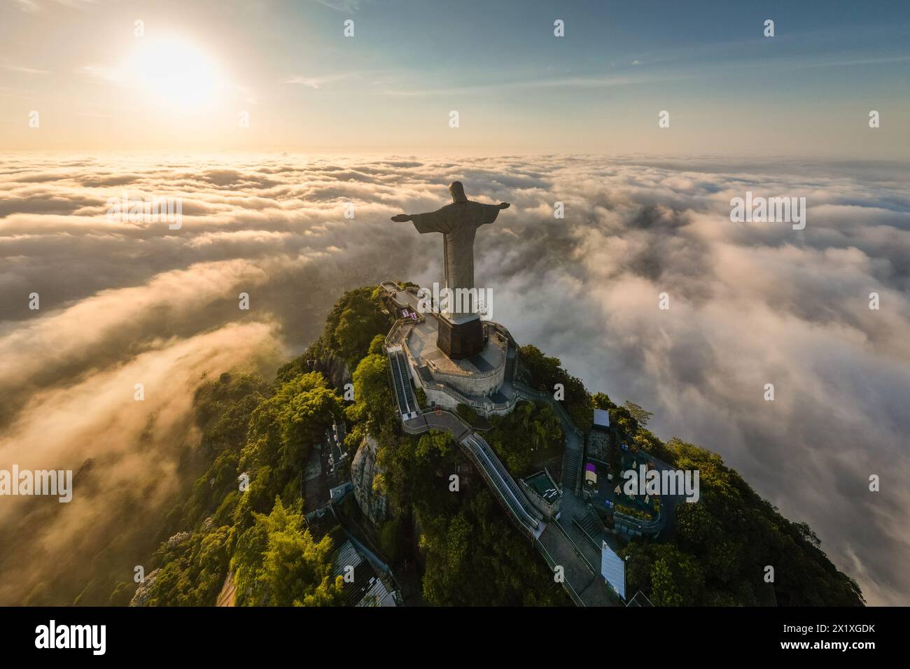 Rio de Janeiro, Brazil - April 11, 2024: Dramatic view of Christ the Redeemer statue on top of the Corcovado mountain above clouds during sunrise. Stock Photo