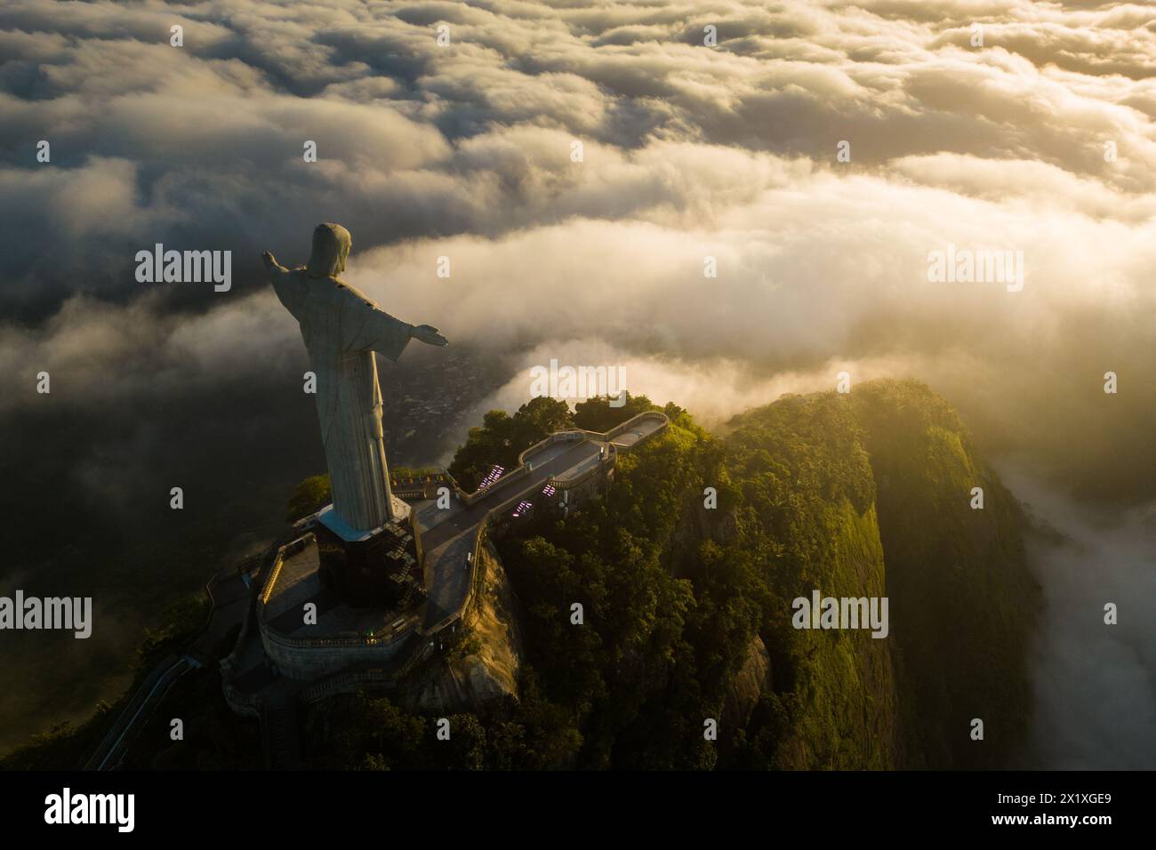 Rio de Janeiro, Brazil - April 11, 2024: Dramatic view of Christ the Redeemer statue on top of the Corcovado mountain above clouds during sunrise. Stock Photo
