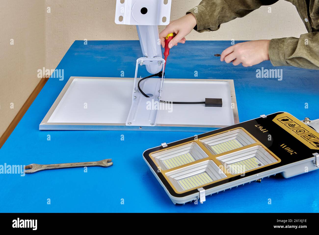 Assembling stand alone solar street light, an electrician attaches solar module and LED luminary to light arm or mounting bracket. Stock Photo