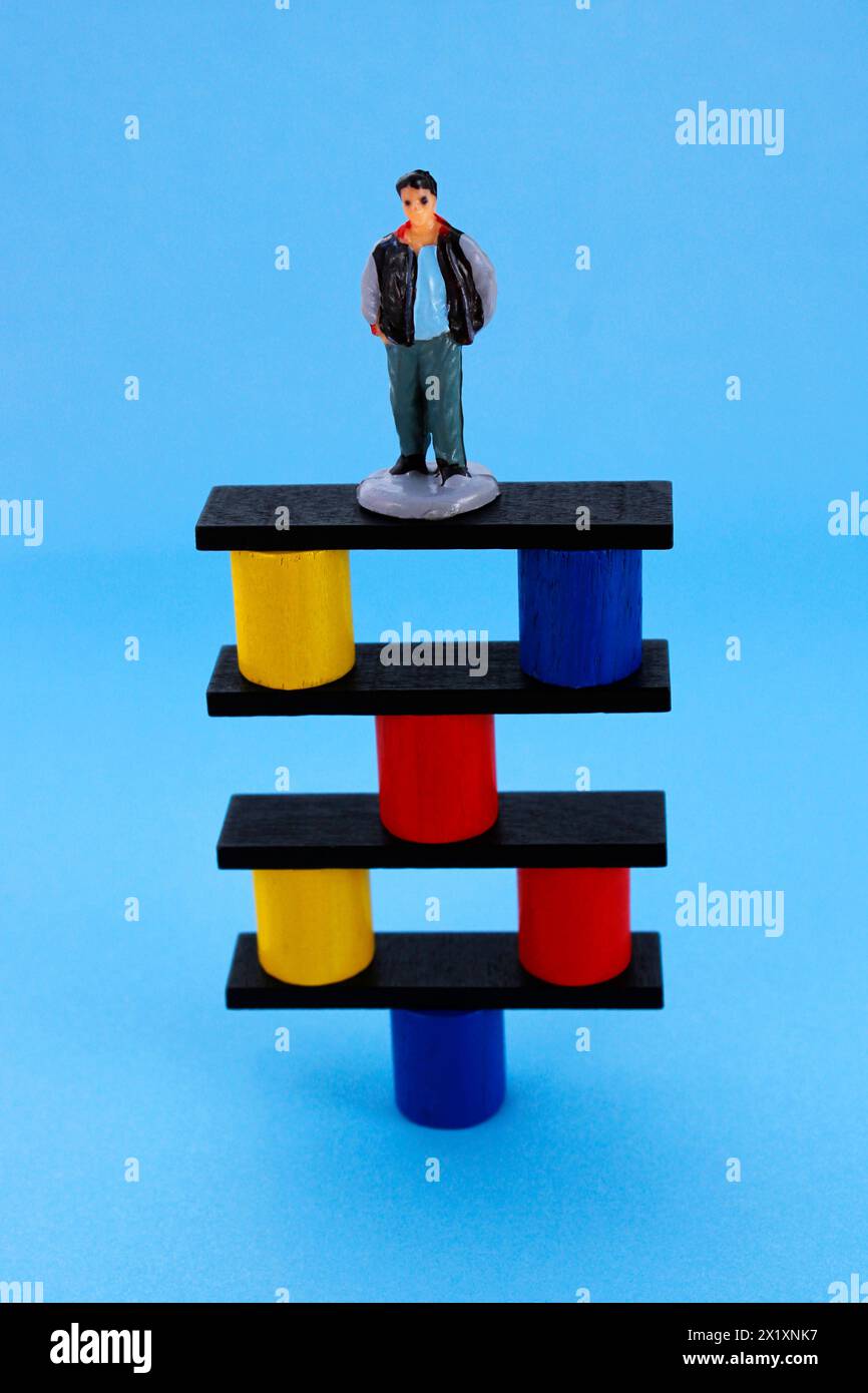 Man on structure balanced on a support point (plastic human figure) Stock Photo