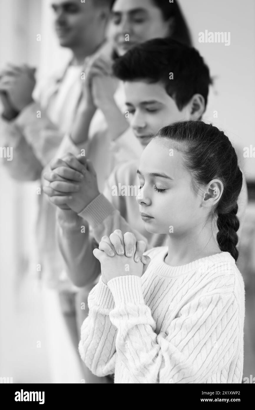 Little girl praying with her family at home, closeup Stock Photo