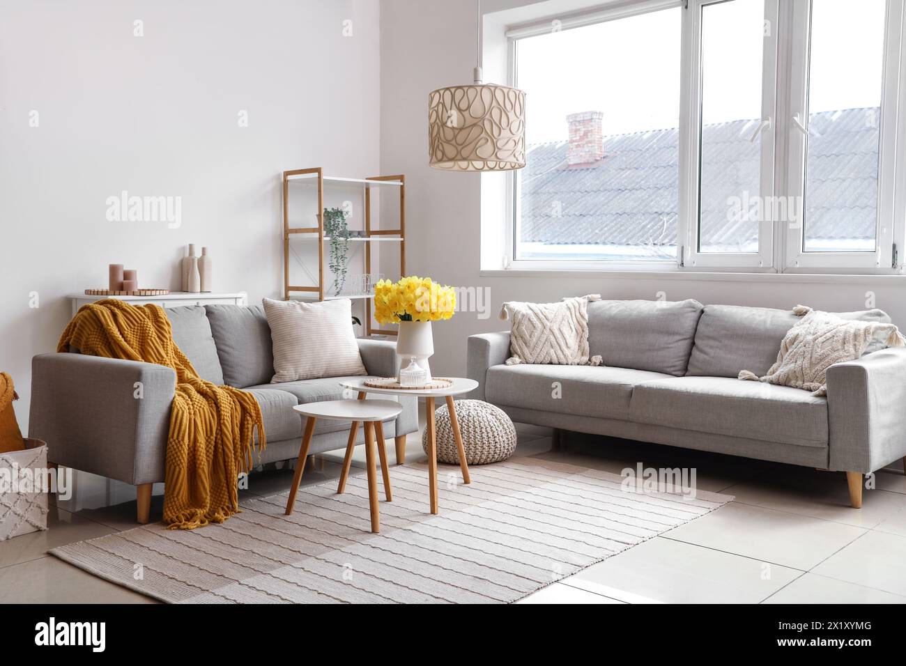 Interior of beautiful living room with sofas, bouquet of narcissus flowers and coffee table Stock Photo