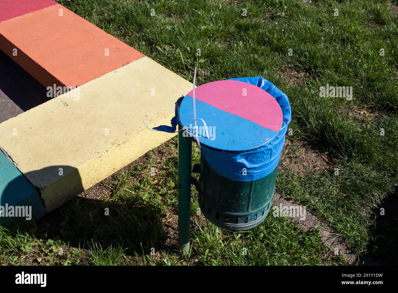 Colorfull waste bin and low wall in a public garden in Italy. Stock Photo