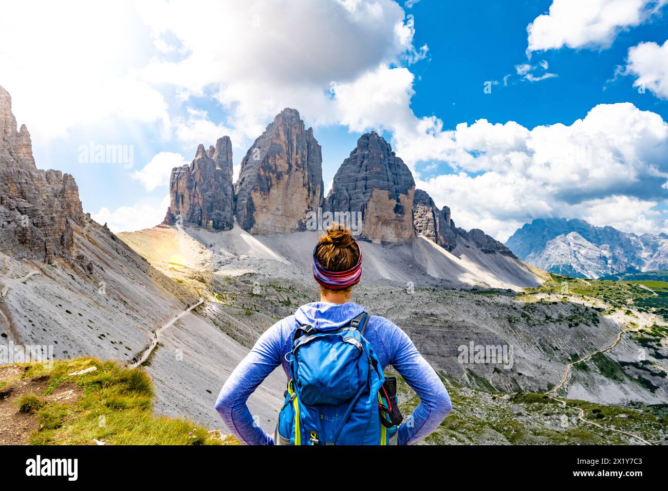 Description: Young athletic woman enjoys view on Tre Cime mountain range in the morning. Tre Cime, Dolomites, South Tirol, Italy, Europe. Stock Photo