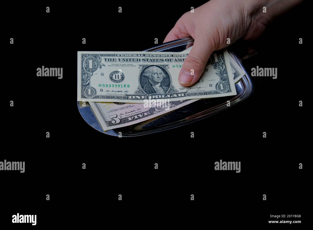 close-up of metal plate with bill and tip, American dollars on black background, slow motion rotation, selective focus, concept of lunch in restaurant Stock Photo