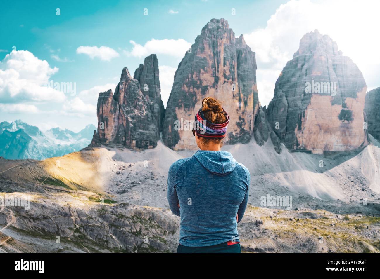 Description: Young athletic woman enjoys view on Tre Cime mountain range in the afternoon. Tre Cime, Dolomites, South Tirol, Italy, Europe. Stock Photo