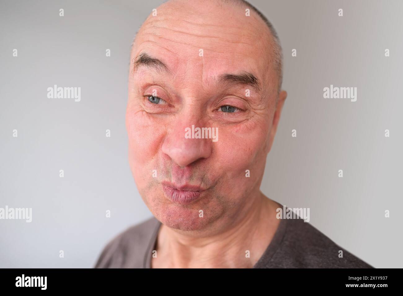 face of a European old man close up, wrinkles on the aging skin, bares teeth, makes grimaces, the concept of mental health, cosmetology, age-related c Stock Photo