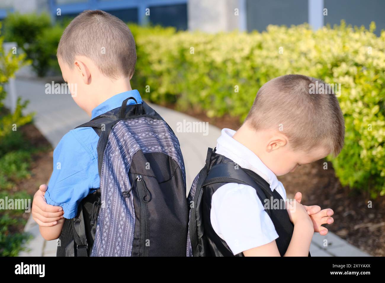 two boys, schoolchildren in black clothes with their faces covered by a medical mask quarreled, turned away, the concept of a quarrel and reconciliati Stock Photo