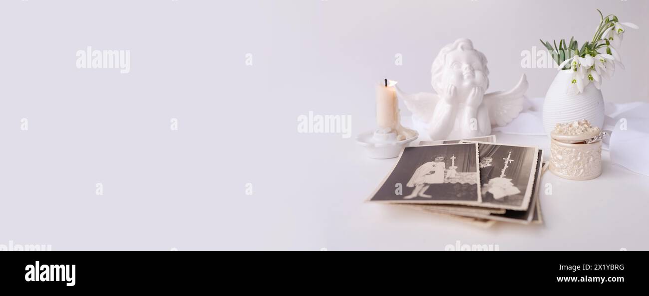 panorama, banner of stack of vintage photos, pictures of children of first communion of 1950, candle is lit, spring flowers in vase, concept of family Stock Photo