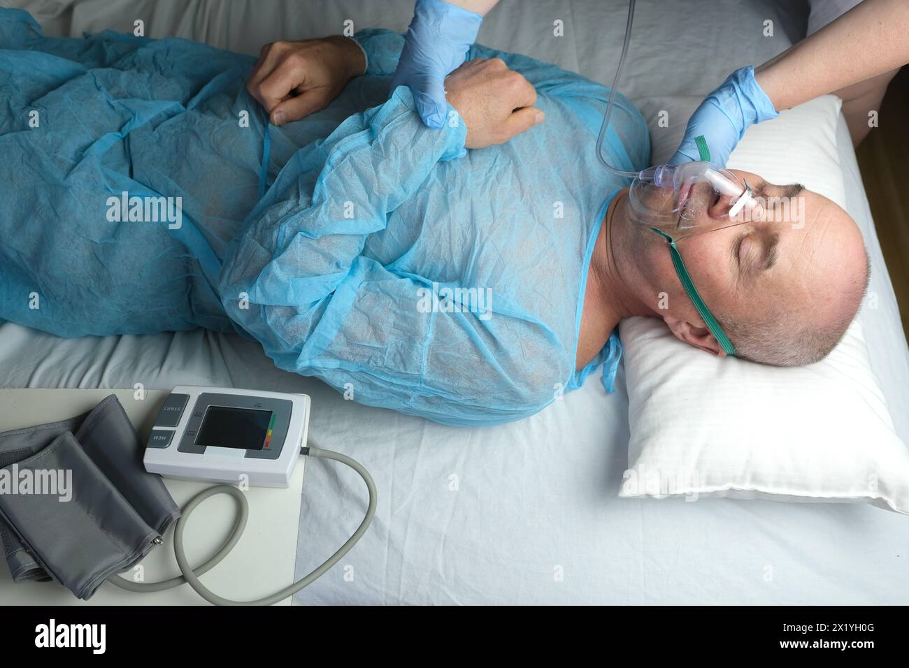 elderly man patient in blue shirt lies, the doctor puts on facial ...