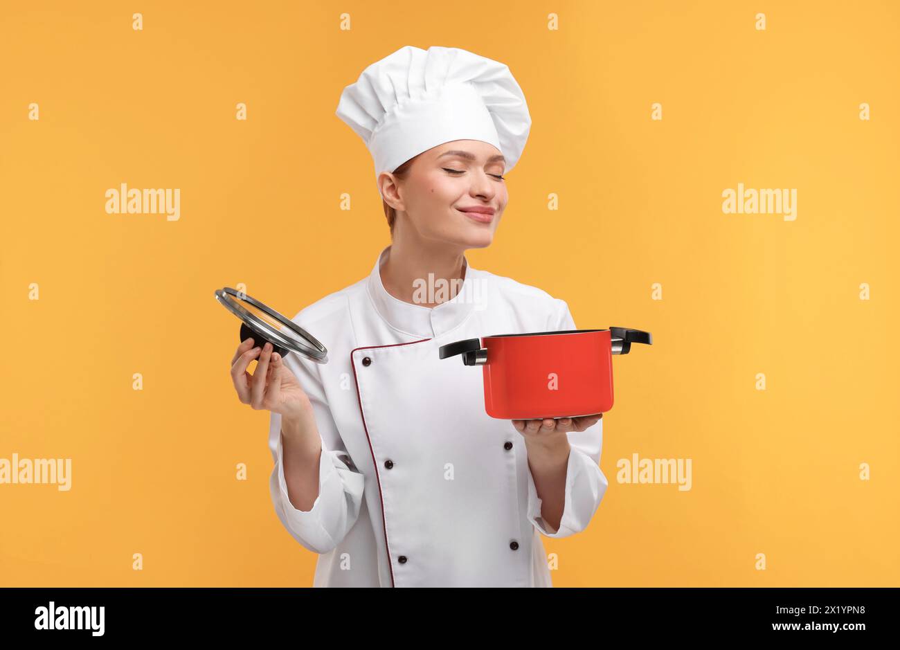 Chef Using Pot Happy chef in uniform holding cooking pot on orange background Stock ...