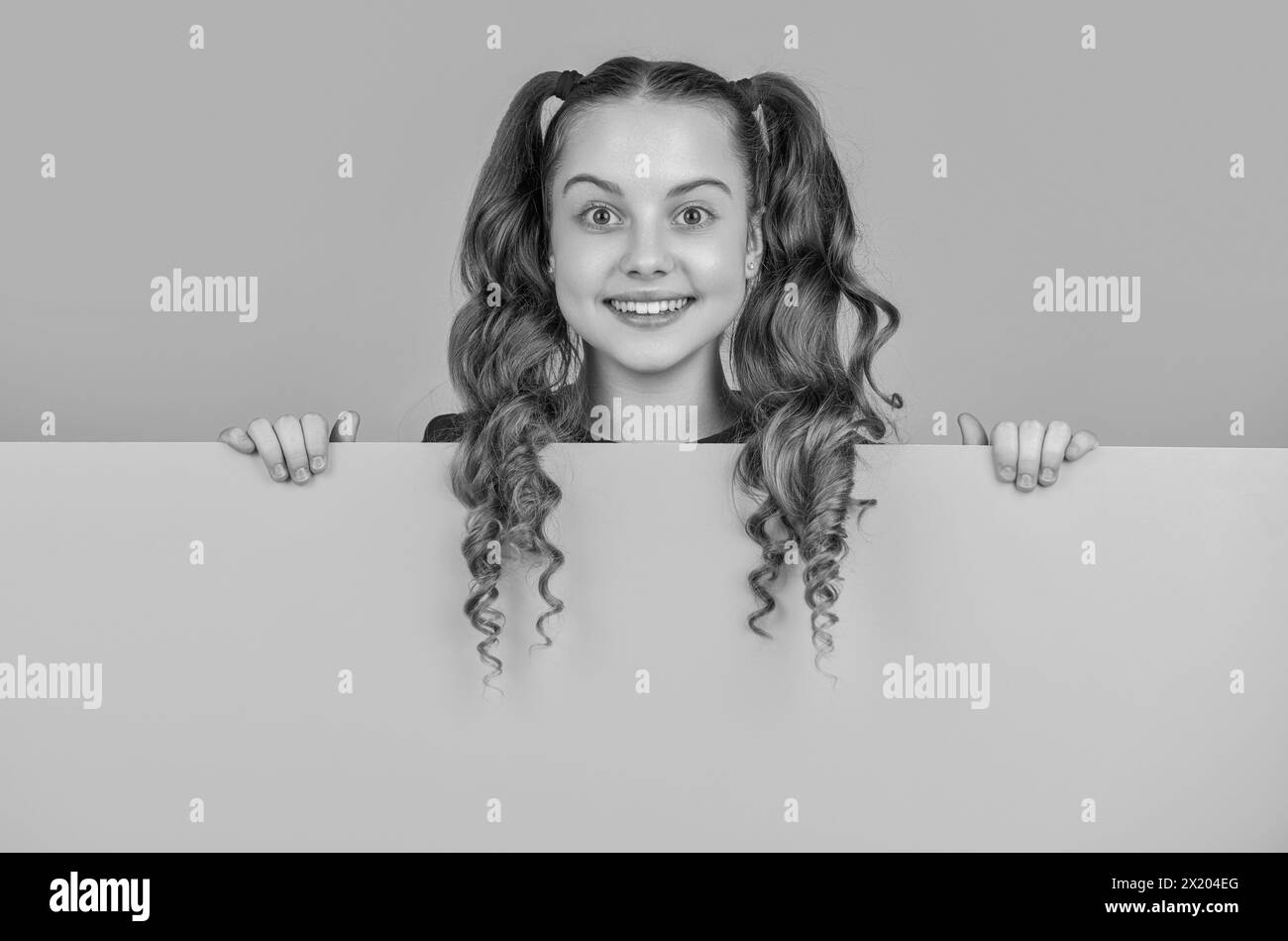 happy kid behind blank yellow paper with copy space for advertisement