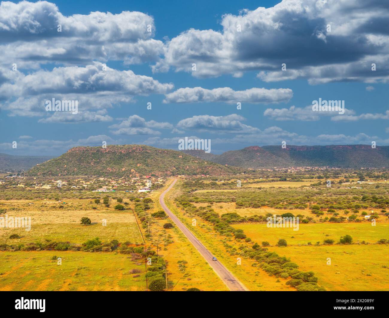 aerial view of typical african landscape, village with hill with bushveld with acacia trees and mountains range in the background Stock Photo