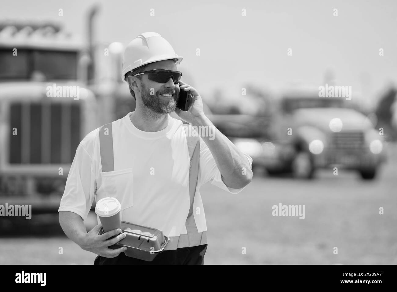 smiling construction site and worker with coffee. caucasian construction manager. Worker with phone at construction site. employee construction man in Stock Photo