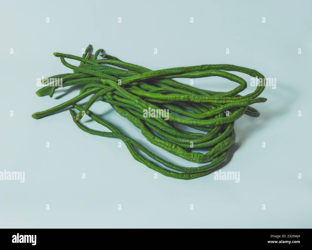 A close-up photo of a bunch of fresh green beans on a white background ...