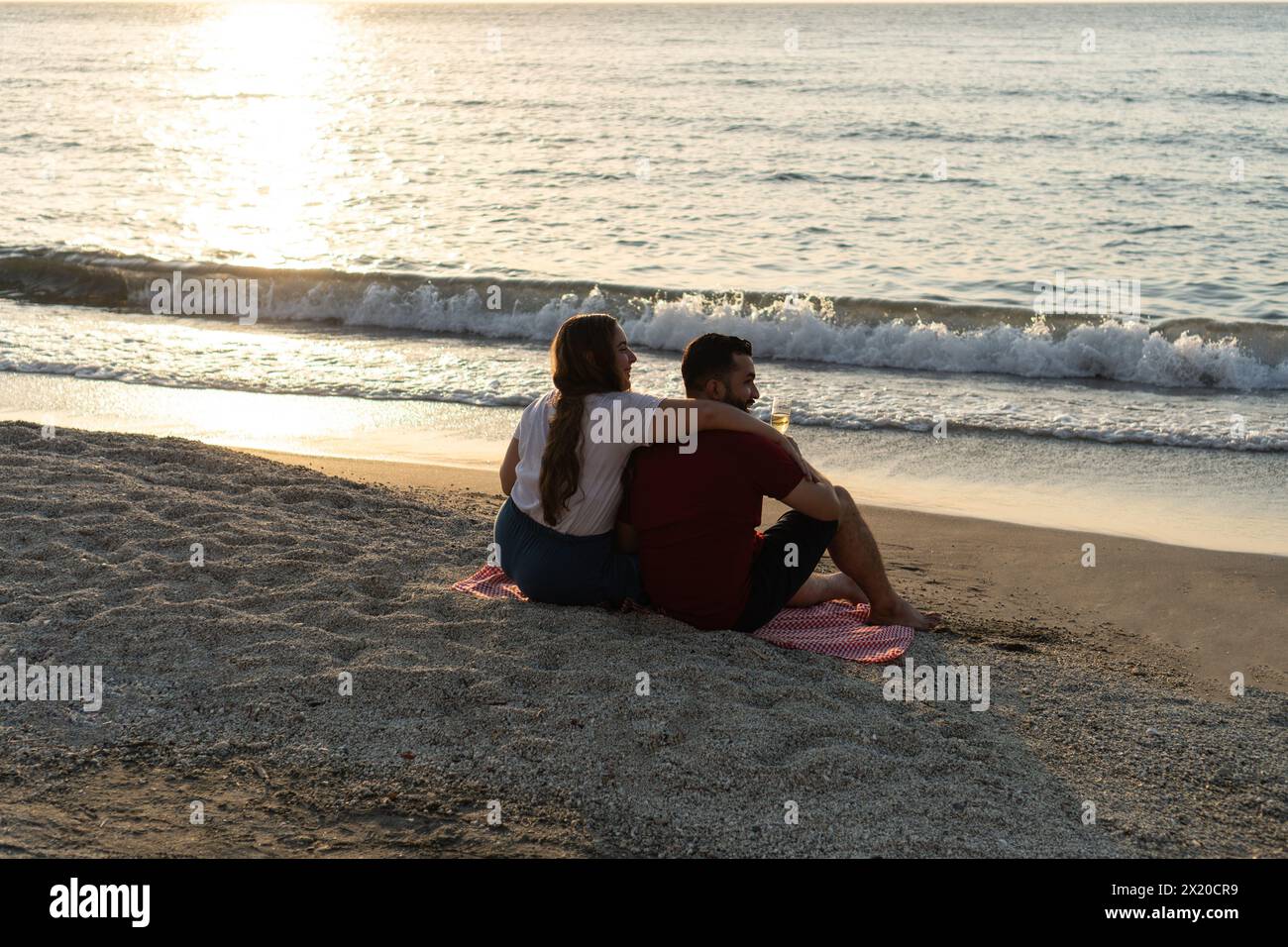 Couple embracing and watching the sunset on a quiet beach Stock Photo ...