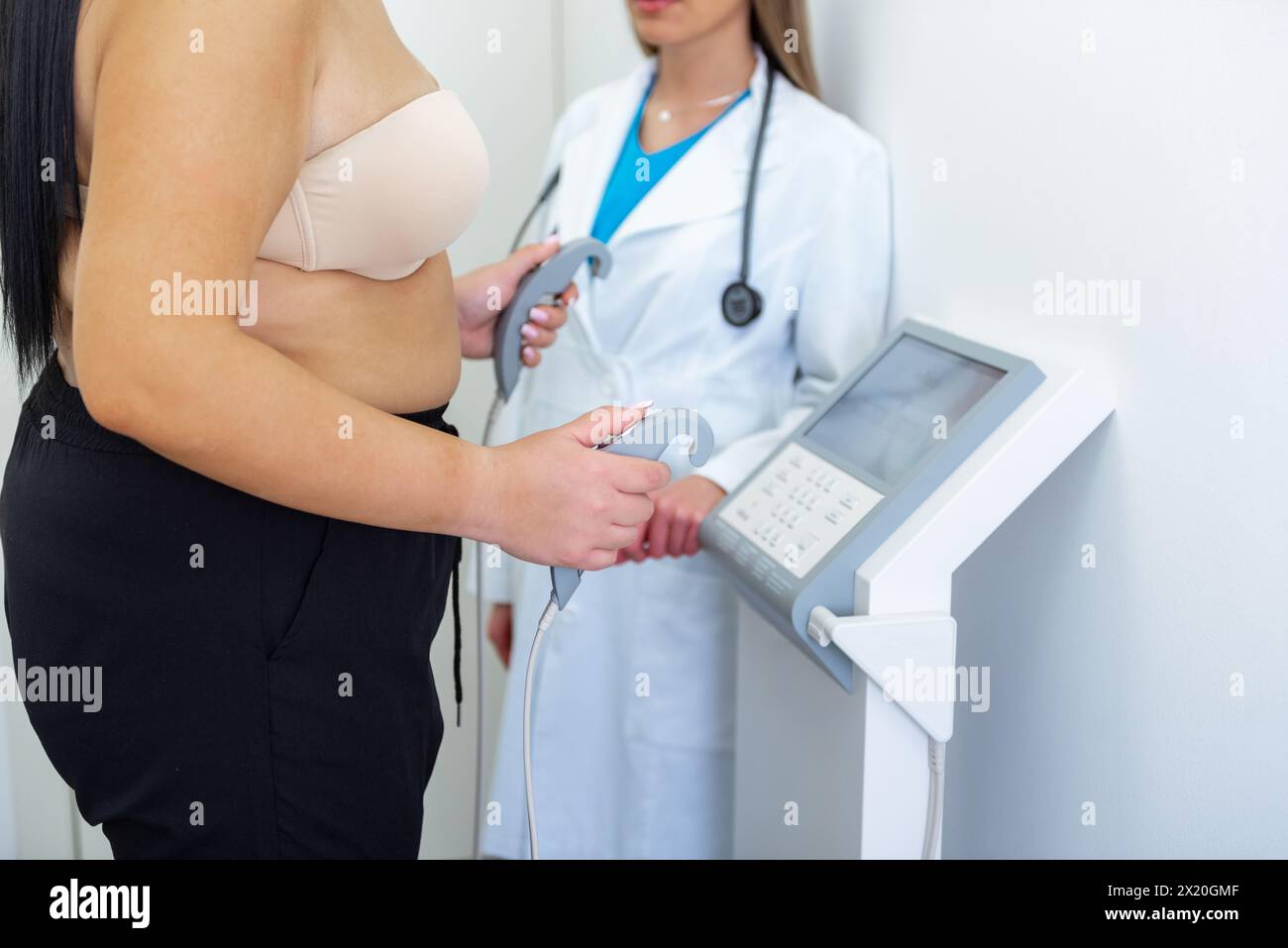 A health practitioner assists a woman with a body composition test using advanced equipment. Stock Photo