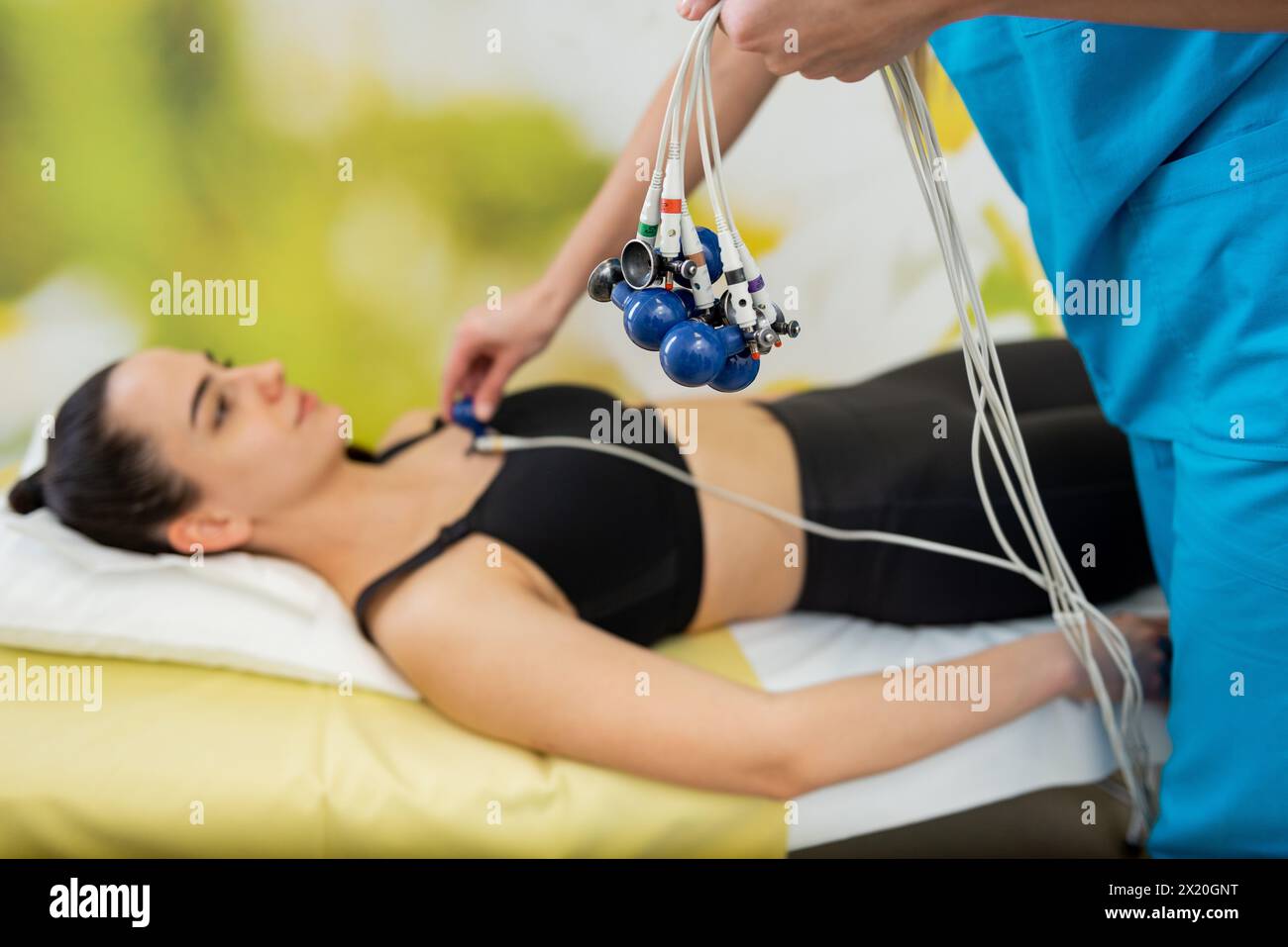 A patient relaxes while a medical professional carefully administers an ECG test. Stock Photo