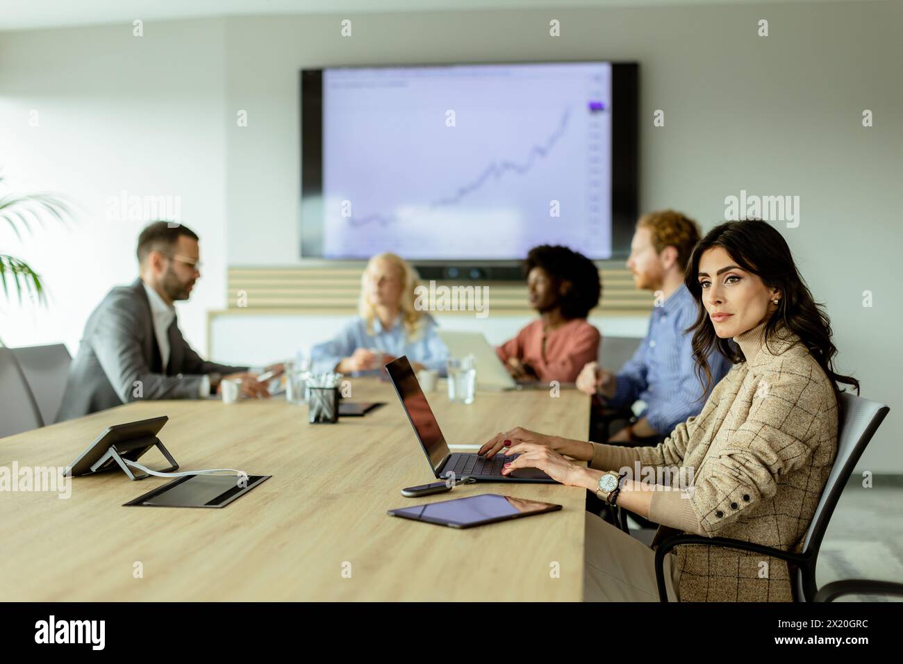 A professional team analyzes growth trends in a modern conference room with a digital display. Stock Photo