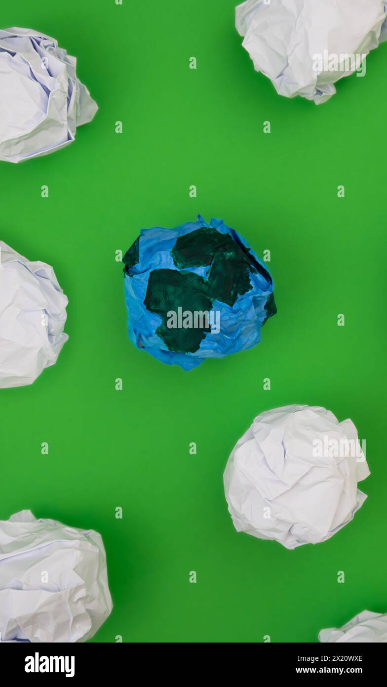Planet earth made of paper on a vibrant green backdrop. Stock Photo