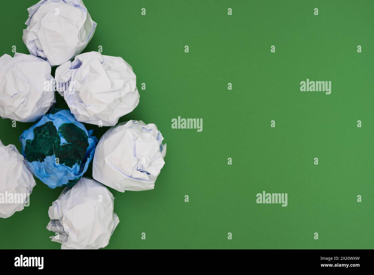 Numerous white paper scattered across a vibrant green surface, copy space. Earth day concept. Stock Photo