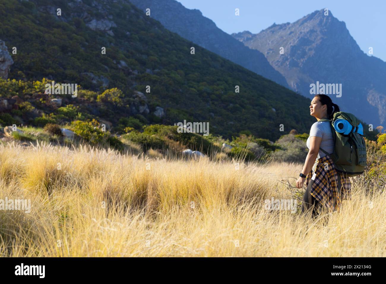 Biracial female hiker enjoying nature, standing in tall grass, with copy space Stock Photo