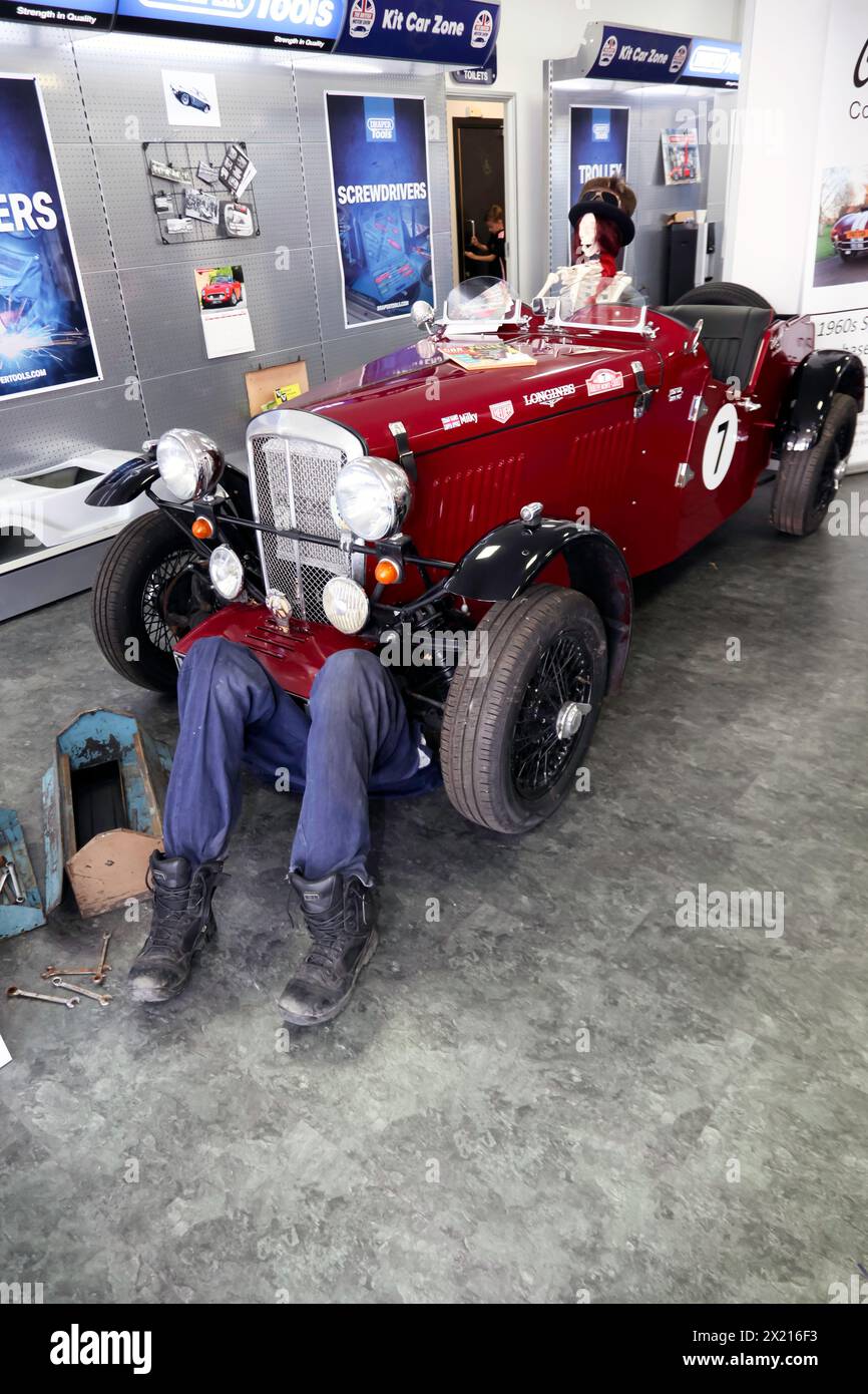 An amusing tableaux  showing a mechanic under a pre-war sport car  with a skeleton in the cockpit, at the 2023 British Motor Show Stock Photo
