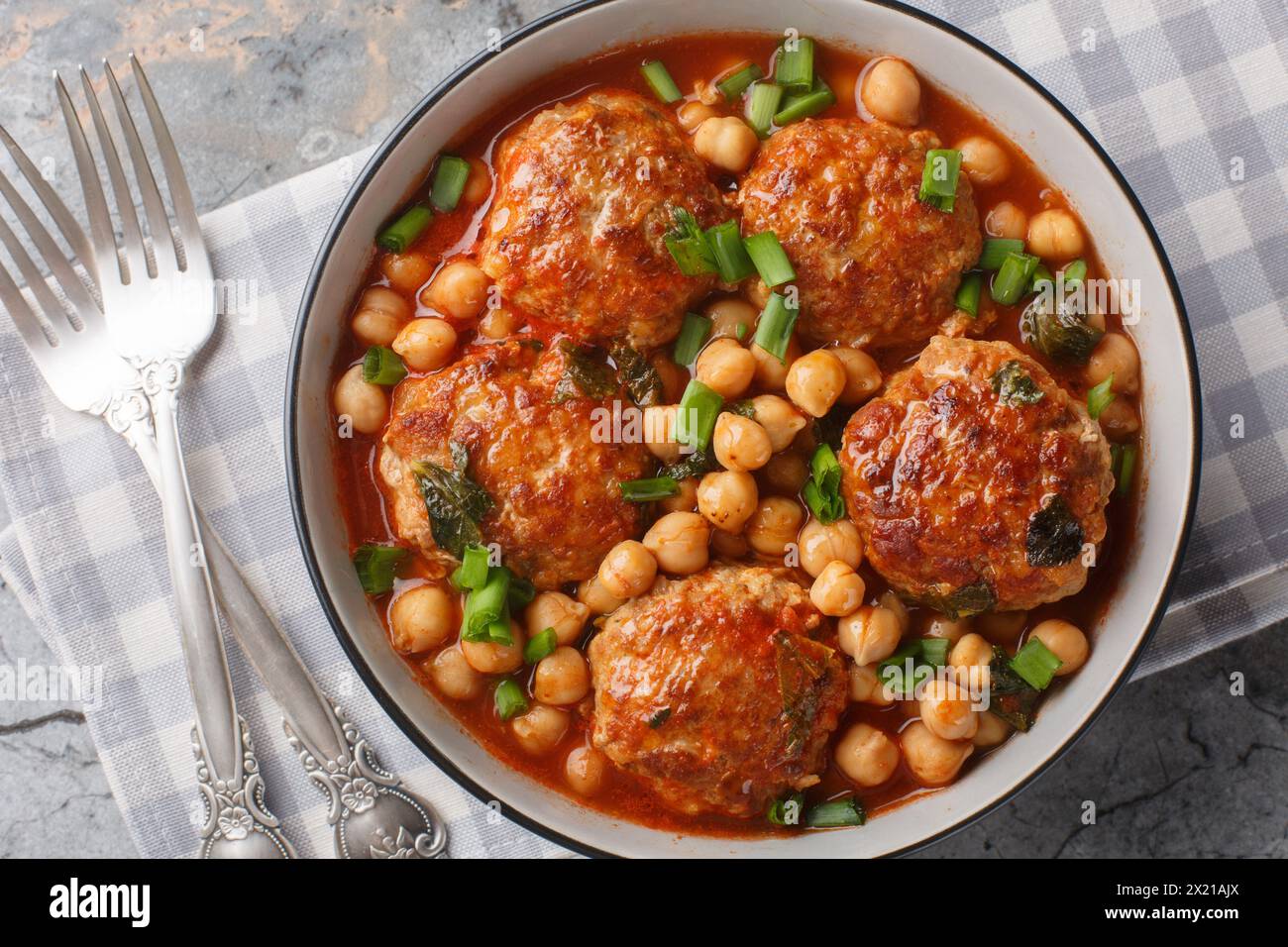 Mediterranean food Lamb meatballs served with chickpeas, tomato and green onions close-up in a bowl on the table. Horizontal top view from above Stock Photo