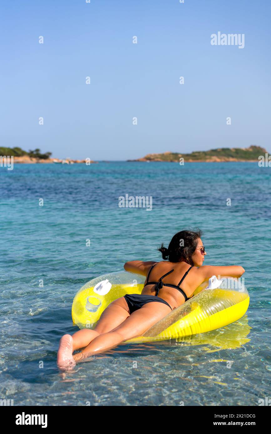 Back view of a woman on a donut inflatable pillow on turquoise water Stock Photo